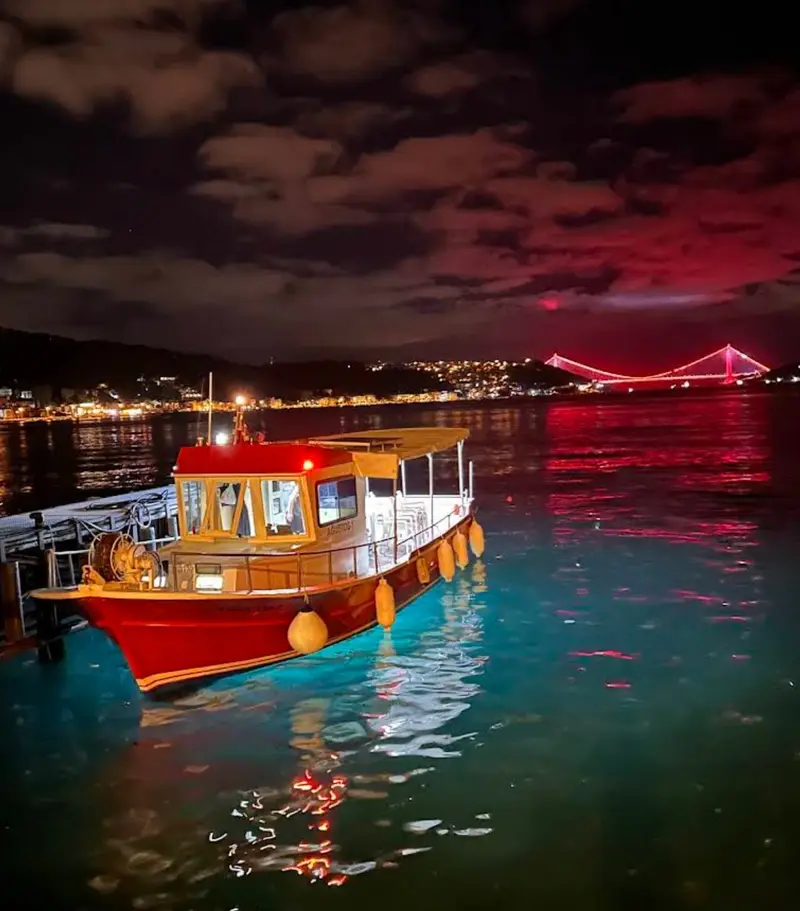 Kırmızı teknemiz ve gece ışıklarıyla Boğaz Köprüsü