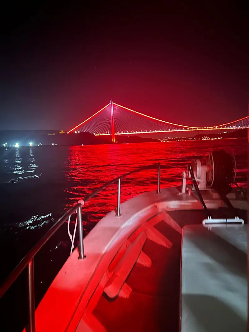 Tekne güvertesinden gece kırmızı ışıklarla aydınlatılan Boğaz Köprüsü